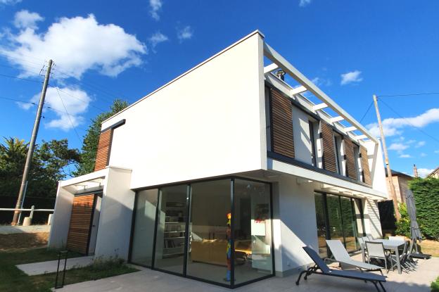 Vue sud-ouest sur jardin. Le séjour est largement vitré, sans poteau d'angle.