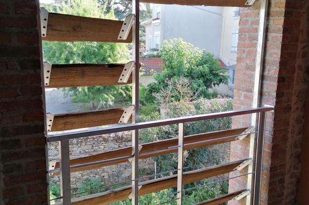 Vue sur l'extérieur à travers un brise vue en bois du site récupéré