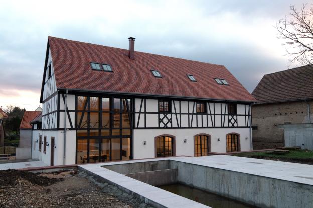Reconstruction d'un corps de ferme alsacien, façade sud moderne avec baie monumentale donnant sur la piscine
