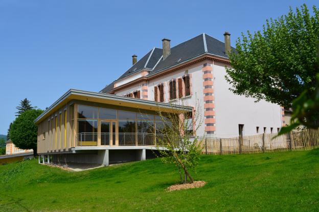 Le restaurant scolaire, en extension de l'école. Porte-à-faux, façade-rideau, bardage prégrisé.