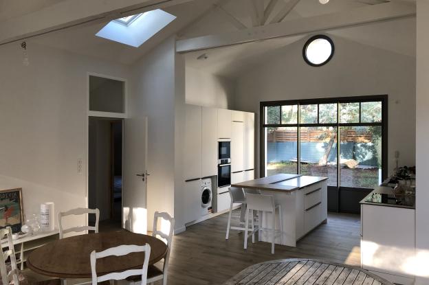 Vue intérieure vers la cuisine, hublot et puits de lumière en toiture, belle hauteur sous toiture
