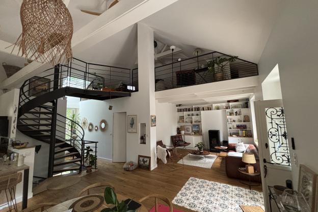 Vue intérieure de l’espace de vie – escalier hélicoïdal, mezzanine et salon en alcôve