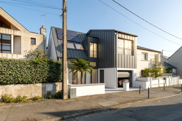 La Maison contemporaine à Rennes issue de la transformation et de la surélévation d’une habitation existante, mêlant volumes épurés, bardage métallique anthracite et grandes ouvertures lumineuses dans une écriture architecturale bioclimatique.