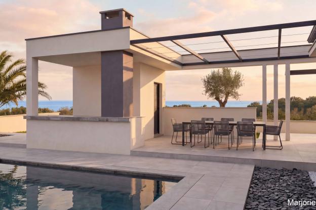 Maison contemporaine haut de gamme d'une surface plancher de 160 m². Volumes épurés en maçonnerie blanche et grise, casquettes et claustras béton, pergola épurée en profils métalliques et câbles noirs.