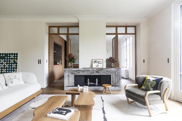 La cheminée, pièce centrale en marbre conçue par l’agence dans un style inspiré des années 1930 et de l’Art Déco, structure l’espace et sépare subtilement la cuisine de la vie commune.