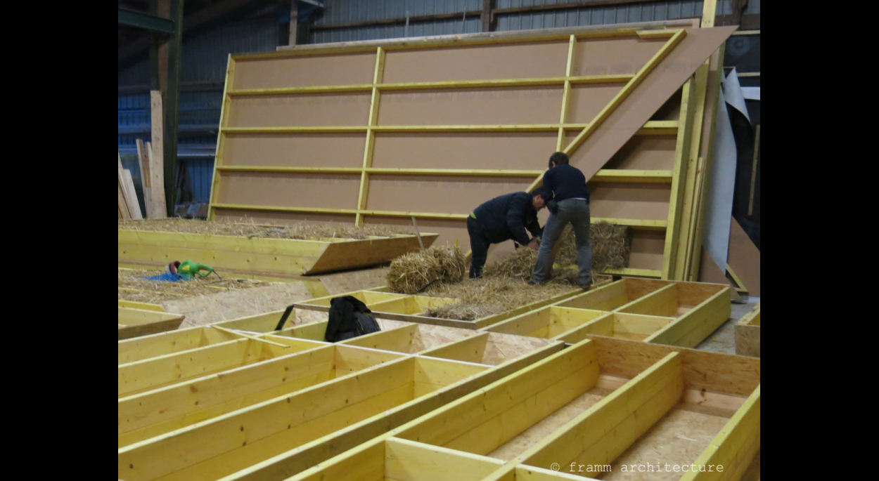 Remplissage des caissons de toiture en paille à l'atelier du charpentier